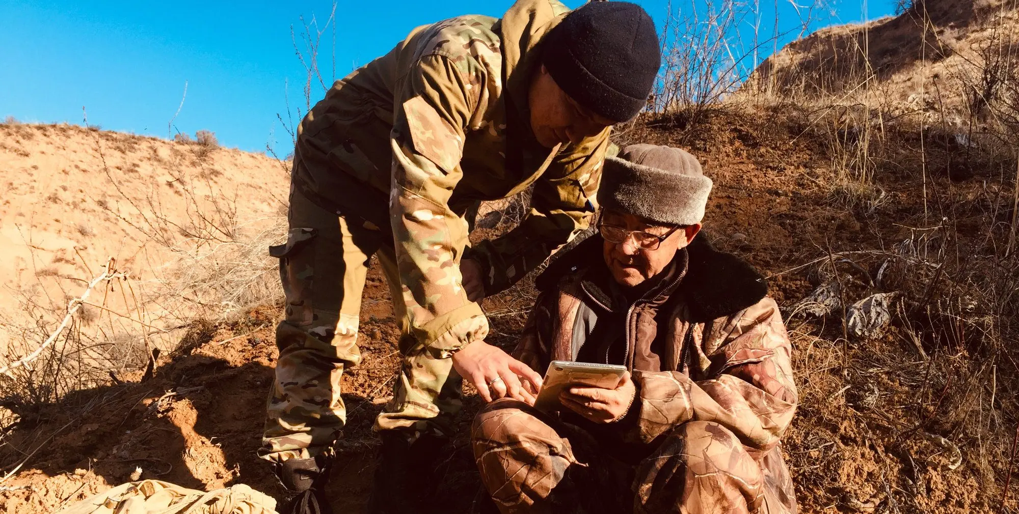 Two members of the inventory team record data on a tablet in the field